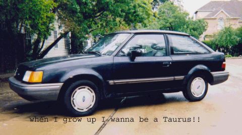1989 Ford Escort - A dark blue hatchback from the 1980s sits parked outdoors, its body style suggesting an earlier model year than claimed.