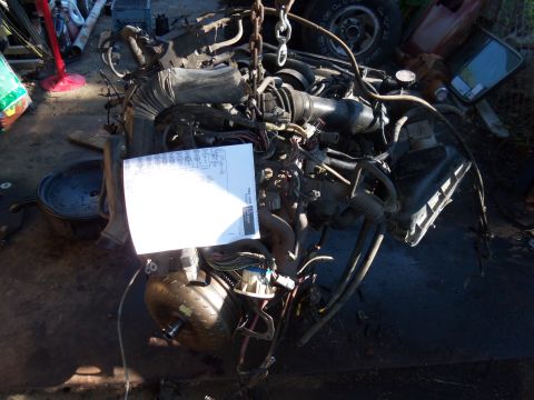 1987 Ford Ranger - An engine and transmission assembly is shown with a wiring diagram placed on top, suspended by a chain.