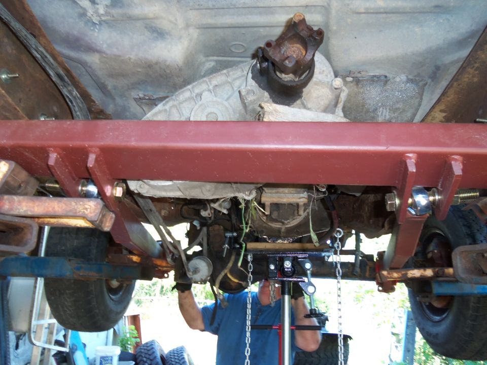 Underbody view of truck transmission and driveshaft being worked on