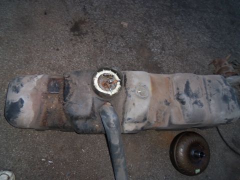 1987 Ford Ranger - Fuel tank and torque converter shown on the ground, likely removed from a vehicle for repair or replacement.