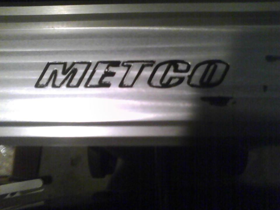 METCO logo on a silver, horizontally ribbed surface