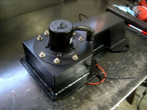 1996 Ford Bronco - A black fuel pump assembly sits on a metal workbench, a motor and electrical wiring.