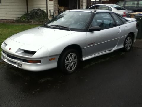 1990 Geo Storm GSi - A silver Geo Storm is parked outside a house on a cloudy day.