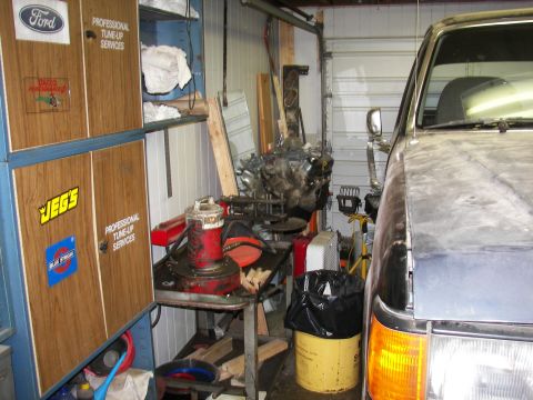 1988 Ford Bronco - A 1988 Ford Bronco is partially visible in a garage, with engine parts and tools in the background.