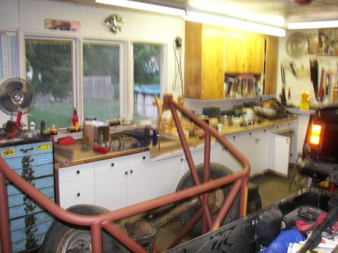 1988 Ford Bronco - Workbench and tools in a garage, with a vehicle's rear and roll cage visible.