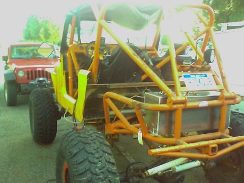 1988 Ford Bronco - A custom buggy with an orange roll cage is parked behind a red Jeep.