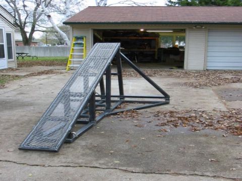 1988 Ford Bronco - A metal ramp sits on a leaf-strewn driveway in front of a garage, with a yellow ladder nearby.