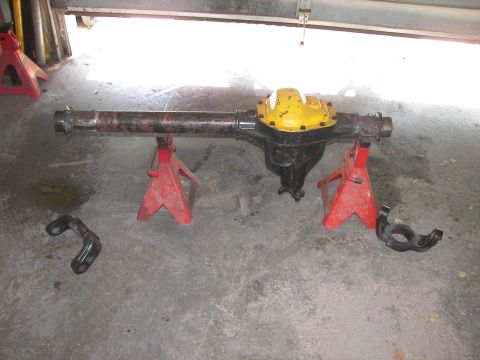 1988 Ford Bronco - Ford rear axle assembly on jack stands, with separate bracket and knuckle components nearby.