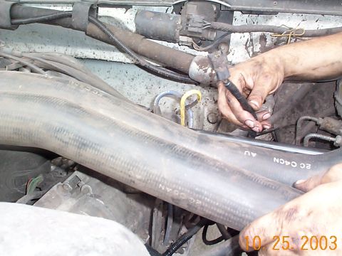 1992 Ford Bronco - Close-up of engine bay components with hands performing maintenance on hoses.