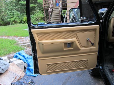 1987 Dodge 1500 - Interior view of a truck door panel, showing the tan upholstery and manual window crank.