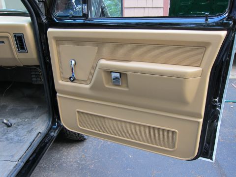 1987 Dodge 1500 - Interior view of the tan door panel, a window crank and chrome door handle, consistent with a 1987 Dodge 1500.