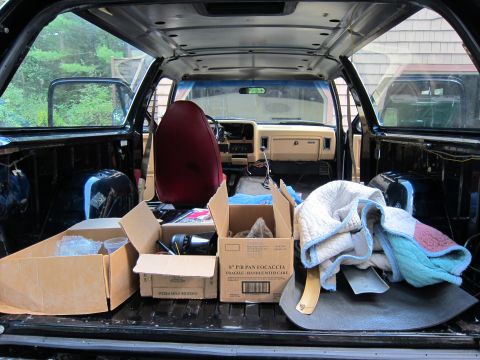 1987 Dodge 1500 - View from the rear of a pickup truck's interior, showing the cabin and bed filled with boxes and blankets.