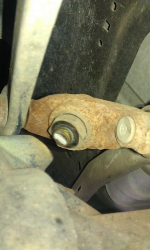 1998 Ford Crown Victoria - Close-up view of a rusted suspension component, showing a bolt with a yellow and black marking.