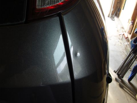 2007 Ford Mustang - A dent is visible on the rear quarter panel of a gray vehicle, with a portion of the taillight in the upper left corner.