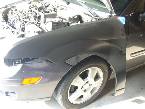2007 Ford Mustang - The front fender of a car is detached, revealing the engine compartment and wheel assembly.