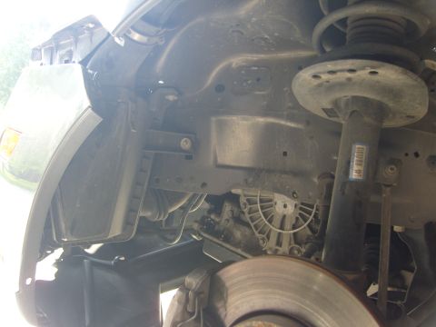 2007 Ford Mustang - Close-up view of the front wheel well and suspension system of a vehicle, including the brake rotor and shock absorber.