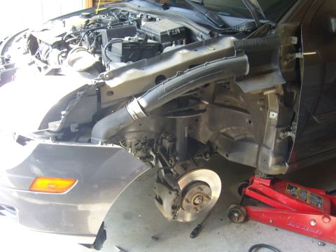 2007 Ford Mustang - Front end of a car is disassembled for repair, showing the engine bay and suspension components.