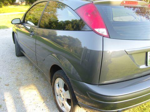 2007 Ford Mustang - Rear view of a gray hatchback car parked on a gravel driveway.