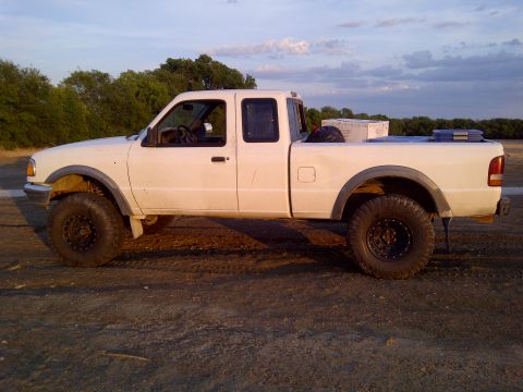1994 Ford Ranger - A white Ford Ranger pickup truck with off-road modifications sits on a dirt road under a cloudy sky.