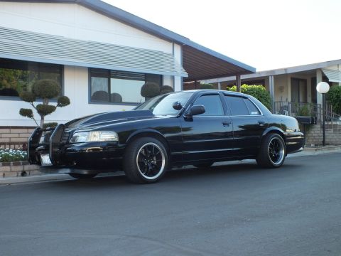 2003 Ford Crown Victoria - Profile of the dark-tinted Crown Victoria parked beside a single-story home.
