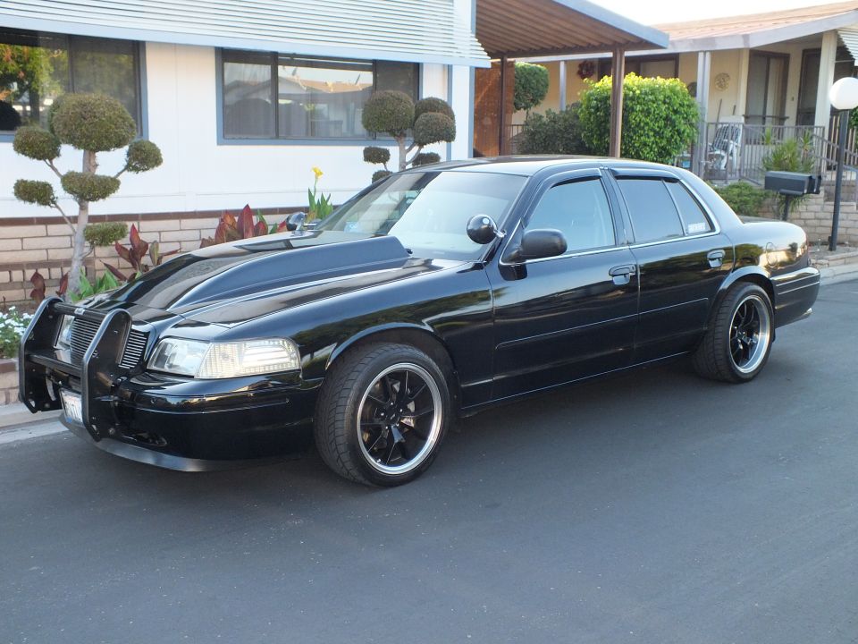 Front three-quarter of black Ford Crown Victoria with grille guard and hood scoop
