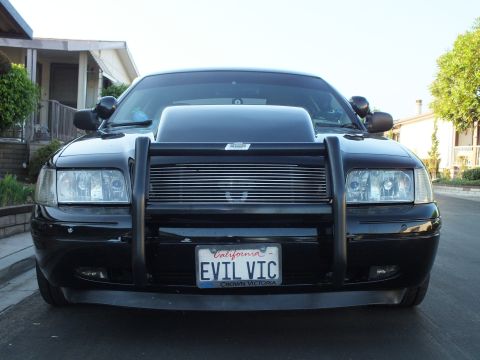 2003 Ford Crown Victoria - Head-on shot of the blacked-out sedan with twin antennas, hood scoop and grille guard.
