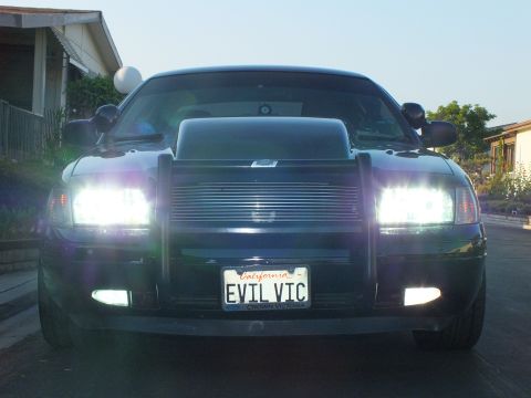 2003 Ford Crown Victoria - Head-on view of the sedan lit up at twilight showing the grille guard and hood scoop.