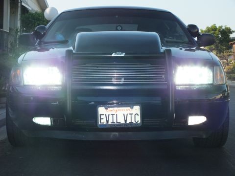 2003 Ford Crown Victoria - Close head-on dusk shot of the blacked-out sedan with all lighting illuminated.