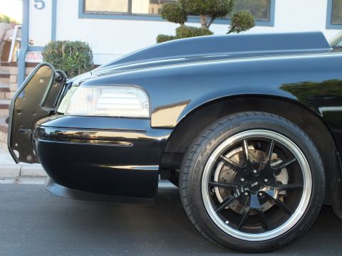 2003 Ford Crown Victoria - Detail of the sedan's front quarter showing headlight, body line and polished-lip black wheel.