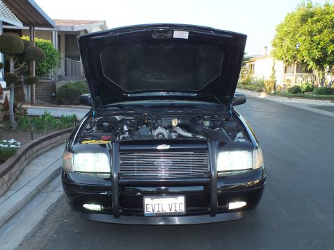 2003 Ford Crown Victoria - Front view of the sedan with the hood raised, exposing the engine bay and grille guard.