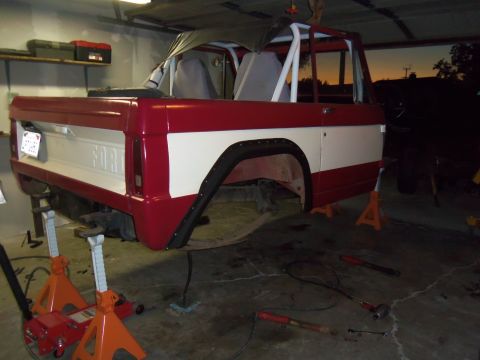 1968 Ford Bronco - 1968 Ford Bronco body undergoing work, supported by jack stands in a workshop setting.