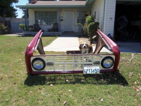 1968 Ford Bronco - A 1968 Ford Bronco front clip sits on a lawn in front of a house, with a dog peeking out from behind the grille.