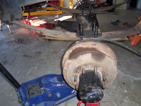 1968 Ford Bronco - Close-up view of a vehicle's rear axle assembly, leaf springs and a brake drum, undergoing maintenance.