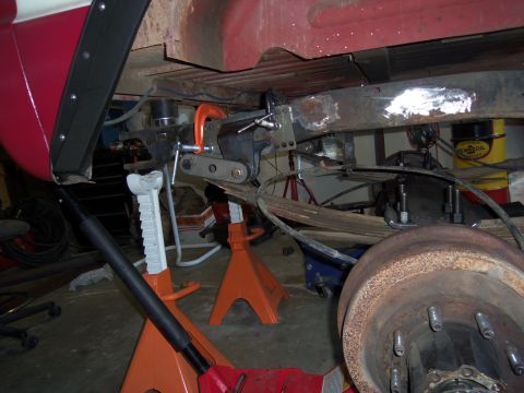 1968 Ford Bronco - Custom suspension work is underway on the underside of a vehicle, supported by jack stands.