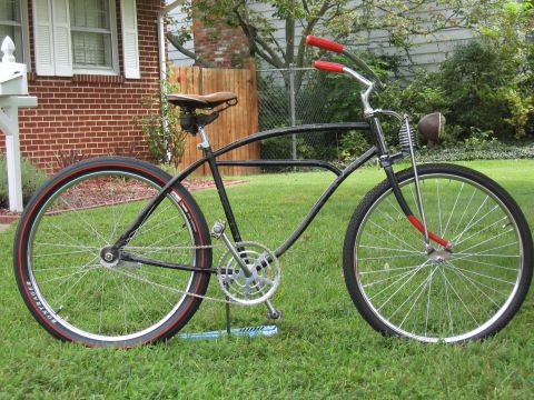 1994 Ford Bronco - A black cruiser bicycle with red handlebars and red-striped tires is parked on a grassy lawn.