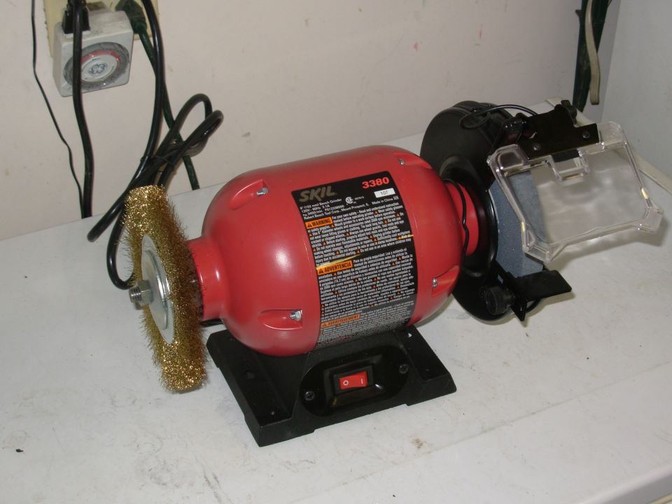 red SKIL 3380 bench grinder with wire wheel on left and grinding stone on right, plugged into a timer