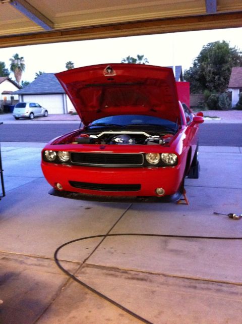 2010 Dodge Challenger - A red 2010 Dodge Challenger is parked in a garage with its hood open, revealing the engine bay.