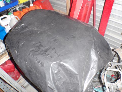 2000 Dodge 1500 - A large object is obscured by a black tarp, surrounded by various containers and shelving in a storage space.