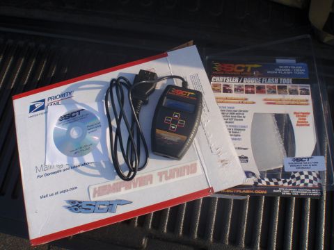 2000 Dodge 1500 - SCT Flash Tool and accompanying CD, likely for vehicle tuning, are laid out on a dark surface.