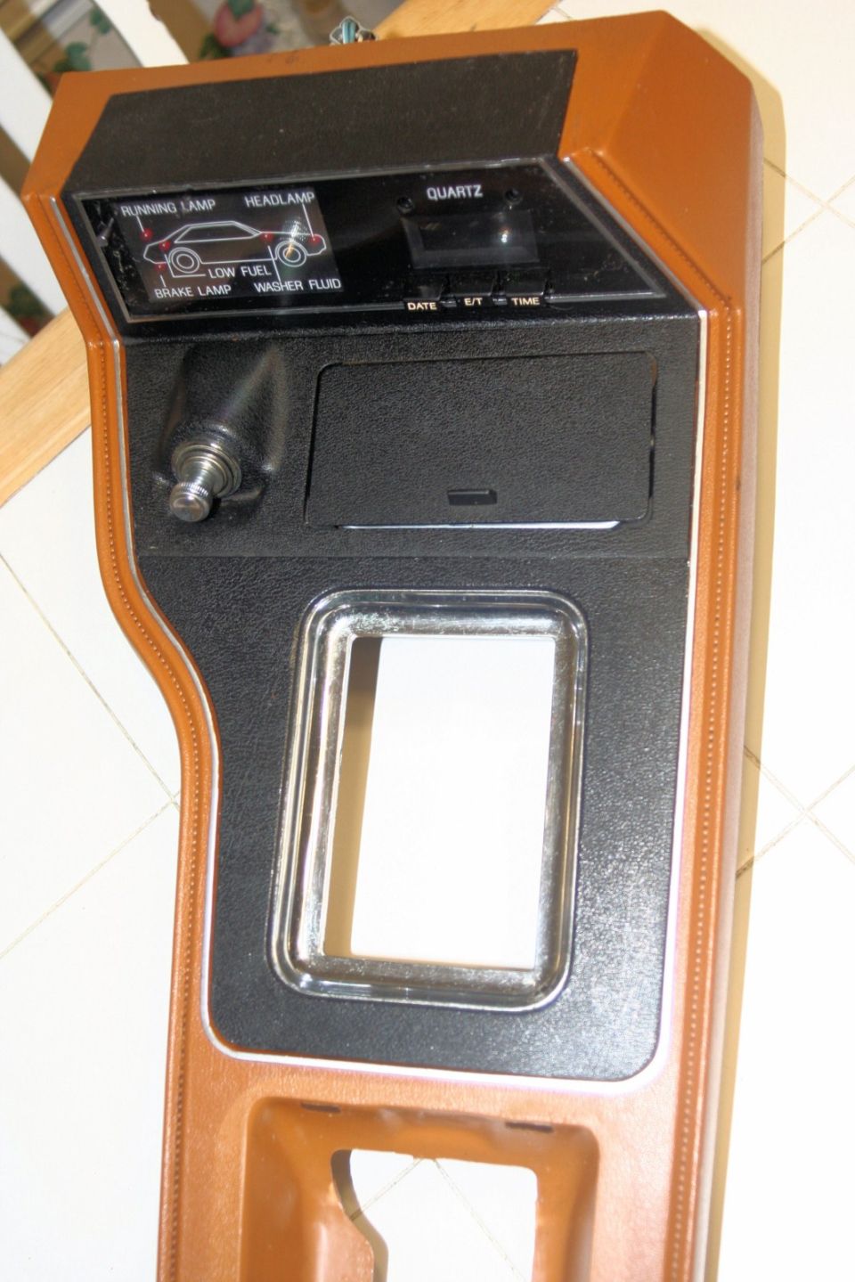 Brown and black dashboard trim with warning lights for running lamp, headlamp, low fuel, and brake lamp, plus a quartz clock