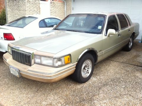 1997 Lincoln Town Car - A 1997 Lincoln Town Car is parked outside a garage, with another vehicle visible to its left.