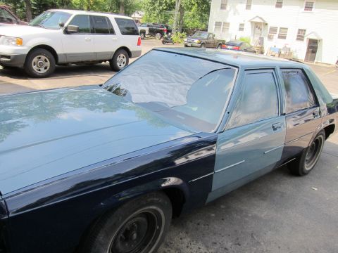 1991 Ford LTD Crown Victoria - A sedan with a two-tone paint job is parked outside, with other vehicles and buildings in the background.