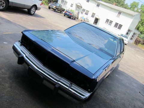 1991 Ford LTD Crown Victoria - A dark sedan sits in a driveway with other vehicles and a house in the background.