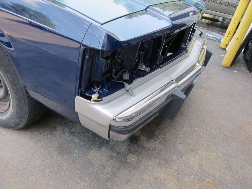 Car's front end, missing grille and headlight assembly. Blue and silver paint