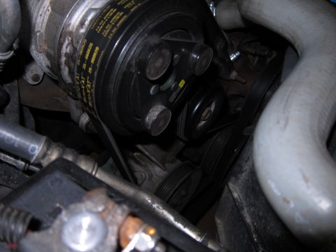 1991 Ford LTD Crown Victoria - Close-up of an engine's air conditioning compressor and associated drive belts.