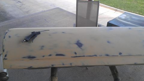 1973 Chevrolet Camaro - A car door, prepped for paint, rests on sawhorses with an air duster on its surface.