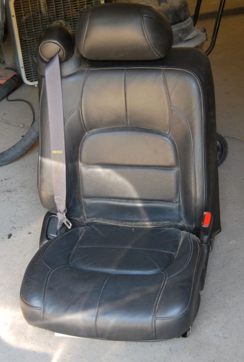 1975 Ford Ranchero - A black leather car seat with a gray seatbelt is shown, possibly for sale or repair.