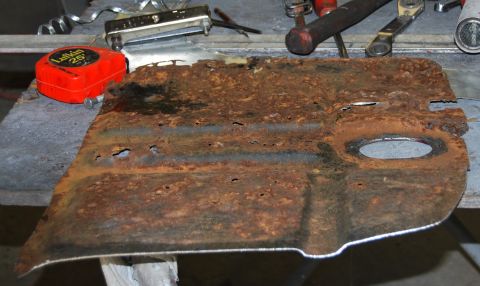 1975 Ford Ranchero - A heavily corroded metal part lies on a workbench, surrounded by tools, suggesting a repair or restoration project.