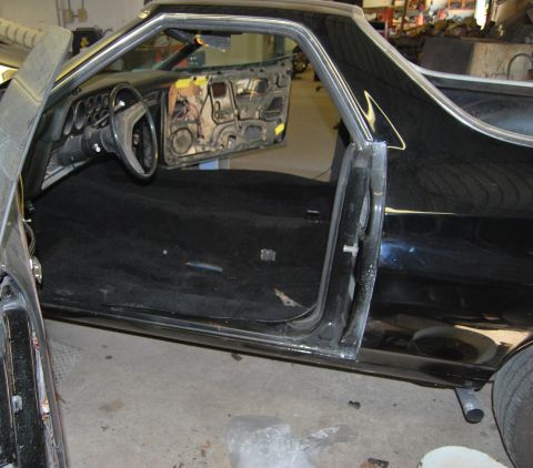 1975 Ford Ranchero - The interior of a 1975 Ford Ranchero shows exposed door panels and a black carpeted floor.