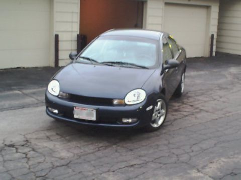 2000 Dodge Neon - A dark blue 2000 Dodge Neon sedan is parked in front of a garage with the doors open.